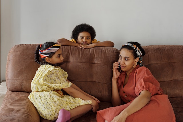 a family sitting on a sofa together with the parent on the phone